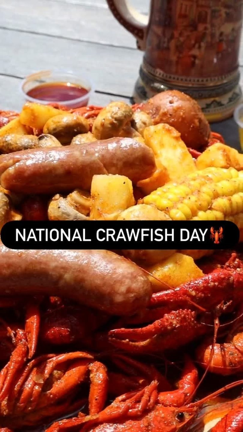 A close-up of a crawfish boil with sausage, corn, potatoes, and mushrooms, with a beer stein in the background.