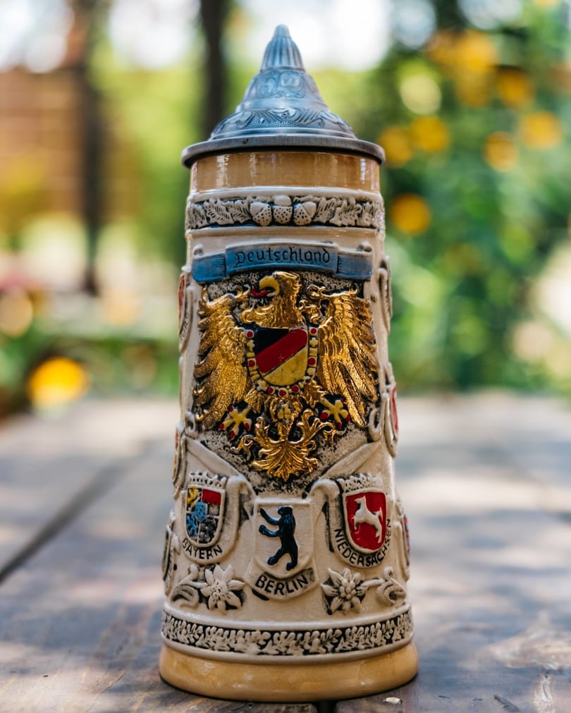 Ornate German beer stein with a golden eagle crest and various city emblems on a wooden table.